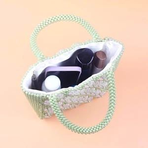 Detail of light green beaded floral bag showing spacious interior with personal items