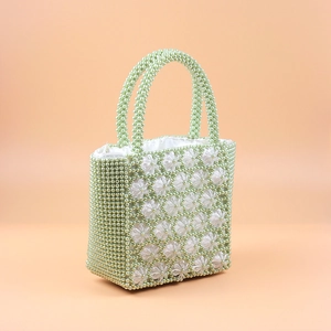 Macro shot of handmade beaded handbag with light green pearls and clear flower details