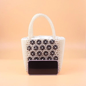 Detail of beaded pearl tote with black flower motifs and phone for size reference