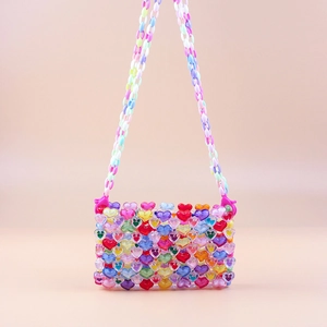 Detail of colorful acrylic heart beads on a handmade woven crossbody mini bag