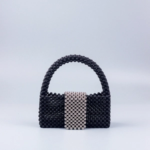 Detail of black beaded handbag featuring silver metallic accents and a woven bead texture