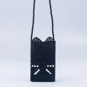Close-up of handmade black beaded crossbody bag with cat ear shape and pearl accents