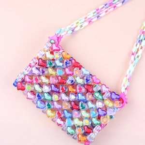 Detail of multi-colored heart-shaped acrylic beads on a handmade woven crossbody bag