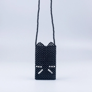 Detail of handmade black beaded crossbody bag with white cat whisker design