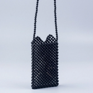 Close-up of black beaded crossbody phone bag with intricate handmade woven texture and strap