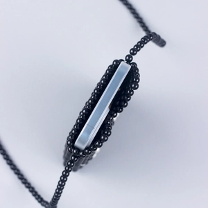 Macro shot of a handmade black beaded crossbody bag holding a silver smartphone