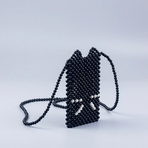 Macro shot of handmade black beaded crossbody bag featuring a cute cat face design