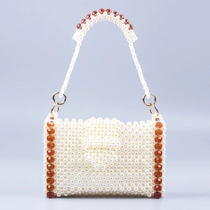 Handmade beaded handbag with white pearls and amber acrylic beads on a blue background