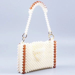 Handmade beaded tote bag with cream pearls and amber crystal accents on a grey background