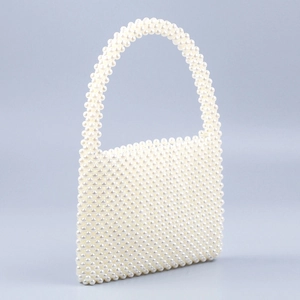 Detailed side view of a handmade pearl beaded handbag with a structured square design