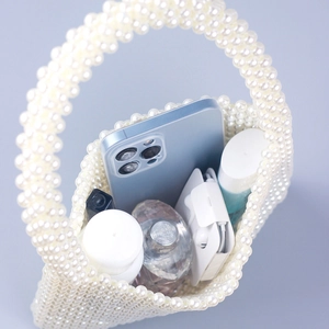 Handmade faux pearl woven handbag showing interior storage for perfume and smartphone
