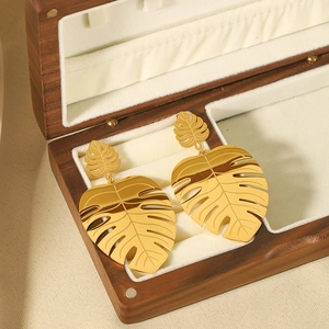 Elegant 18k gold plated stainless steel monstera leaf earrings on a wooden jewelry box