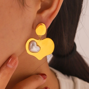 Boucles d'oreilles cœur en or 18k avec détail perle portées par un mannequin femme