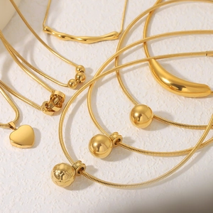 Detailed close-up of various 18k gold plated heart, sphere, and crescent pendants on snake chains
