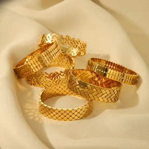 Bracciali rigidi minimalisti in titanio placcato oro 18k con varie trame geometriche su tessuto