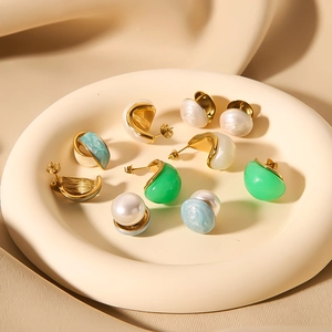 18k gold plated titanium earrings set with turquoise, pearls and green gems on a tray