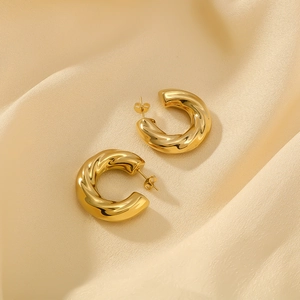 Vue détaillée des boucles d'oreilles créoles C dorées avec une texture torsadée