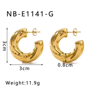 Détail macro de boucles d'oreilles créoles C dorées torsadées à texture miroir