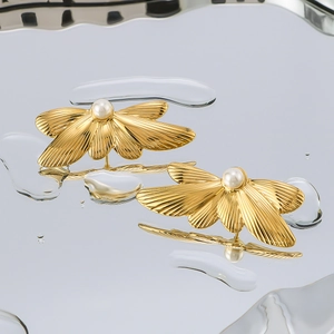 18k gold plated stainless steel wing earrings with center pearl on water droplets background
