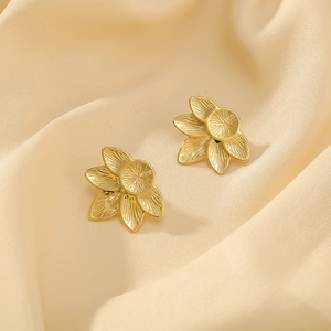 Macro detail of 18K gold plated hexagram flower earrings with radial textured petals