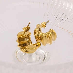 Makro-Detail von 18k vergoldeten Edelstahl-Creolen mit gewellter Croissant-Textur