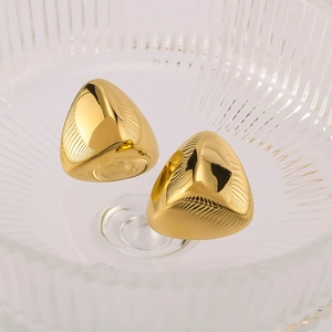 Detailed macro view of 18k gold plated stainless steel triangle earrings on textured glass