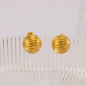 Spherical gold earrings with ribbed texture on clear glass, minimalist style