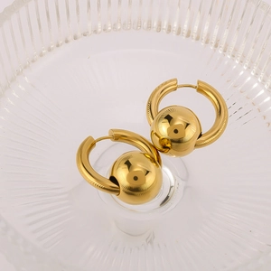 Detailed view of polished 18k gold plated round ball hoop earrings on a textured glass tray