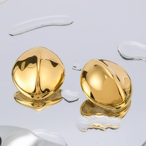Polished 18k gold plated bean shaped stud earrings on a reflective water drop surface