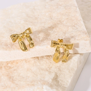 Boucles d'oreilles nœud dorées 18k avec texture ruban sur support en pierre élégant