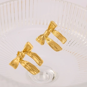Détail macro de boucles d'oreilles nœud dorées avec une texture effet soie délicate