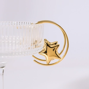 Detail of 18k gold plated crescent moon and star earrings on a glass rim