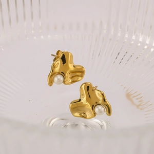Détail d'une boucle d'oreille organique en acier plaqué or 18k ornée d'une perle blanche