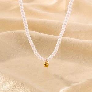 Détail d'un collier de perles avec pendentif haricot doré 18 carats sur soie