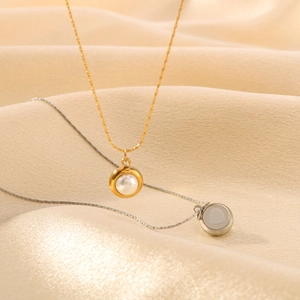 Collar minimalista con perla dorada y colgante de corazón plateado sobre seda suave