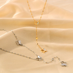 Colliers papillon en or et argent avec zircon sur fond de soie couleur champagne