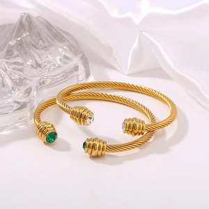 Detailed close-up of 18k gold-plated twisted cable cuff bracelets with colored gemstones