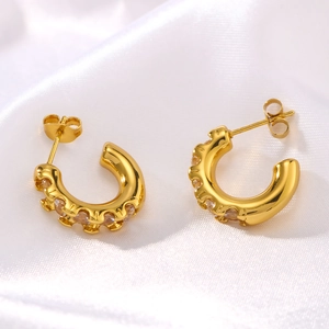 Boucles d'oreilles créoles dorées en C avec zircons incrustés sur tissu en soie blanche