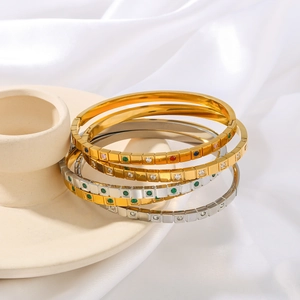 Set of four stainless steel bangles with colorful zircon inlays on cream ceramic tray