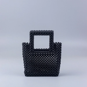 Détail d'un sac à main artisanal en perles noires avec texture tissée et poignée ronde