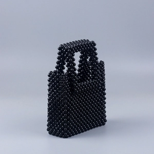 Détail d'un sac à main artisanal en perles noires avec texture tissée et poignée ronde