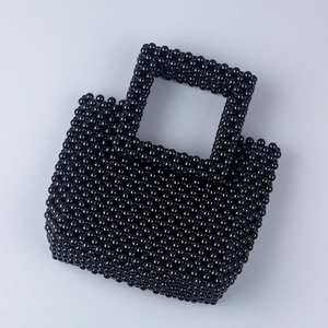 Détail d'un sac à main artisanal en perles noires montrant la texture brillante et le tissage