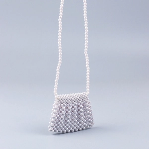 Detailed view of handmade white pearl woven mini crossbody bag with delicate long strap
