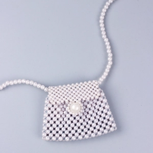Detailed view of handmade mini pearl crossbody bag with beaded strap and flap closure