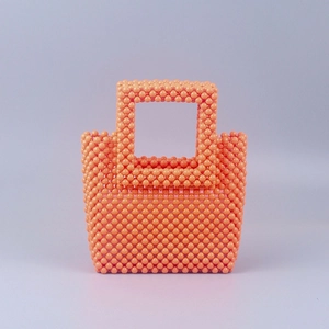 Detailed view of handmade orange acrylic beaded handbag with woven grid pattern