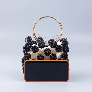 Detail view of black beaded evening bag with golden ring handle and drawstring lining