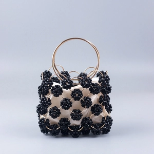 Detail of black beaded ball evening bag with gold metal handle and white satin lining