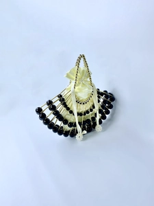 Macro shot of fan-shaped evening bag with black beads and gold metallic frame detail