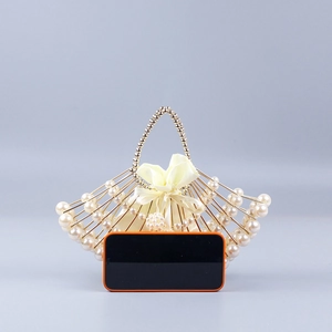 Detail of beaded fan-shaped evening bag showing pearl texture next to a smartphone