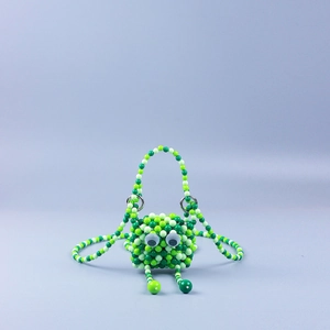 Detail der handgefertigten grünen Perlentasche in Froschform mit 3D-Augen